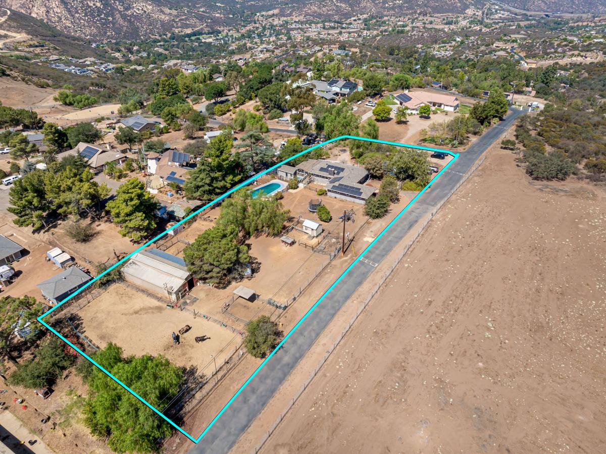 Aerial view of the property showing the barn, pool, home, and open land