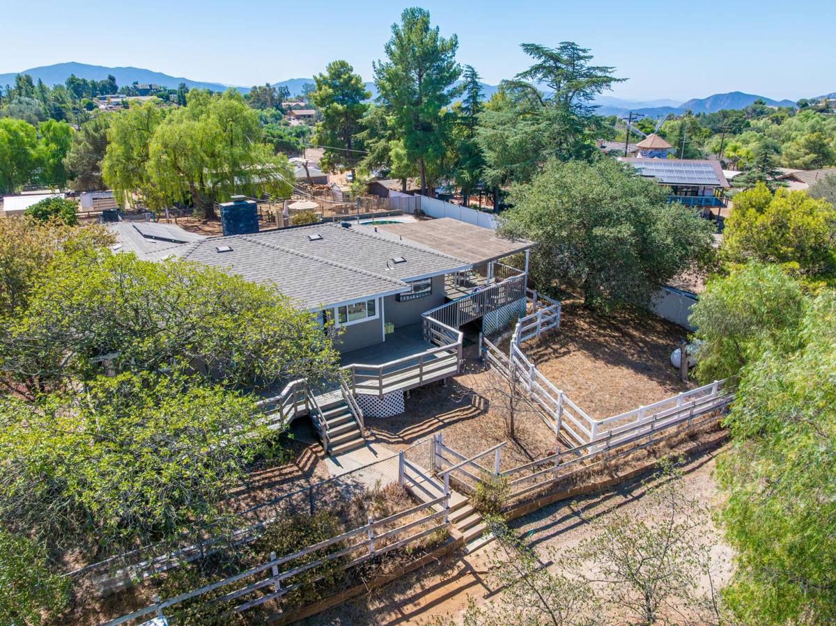 Aerial of the rear deck and fenced yard with mountains beyond