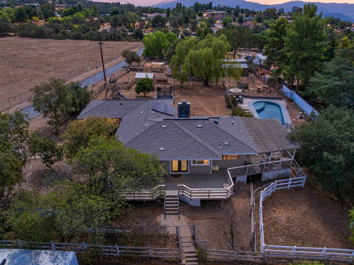 Aerial view of the home, deck, pool, and land behind