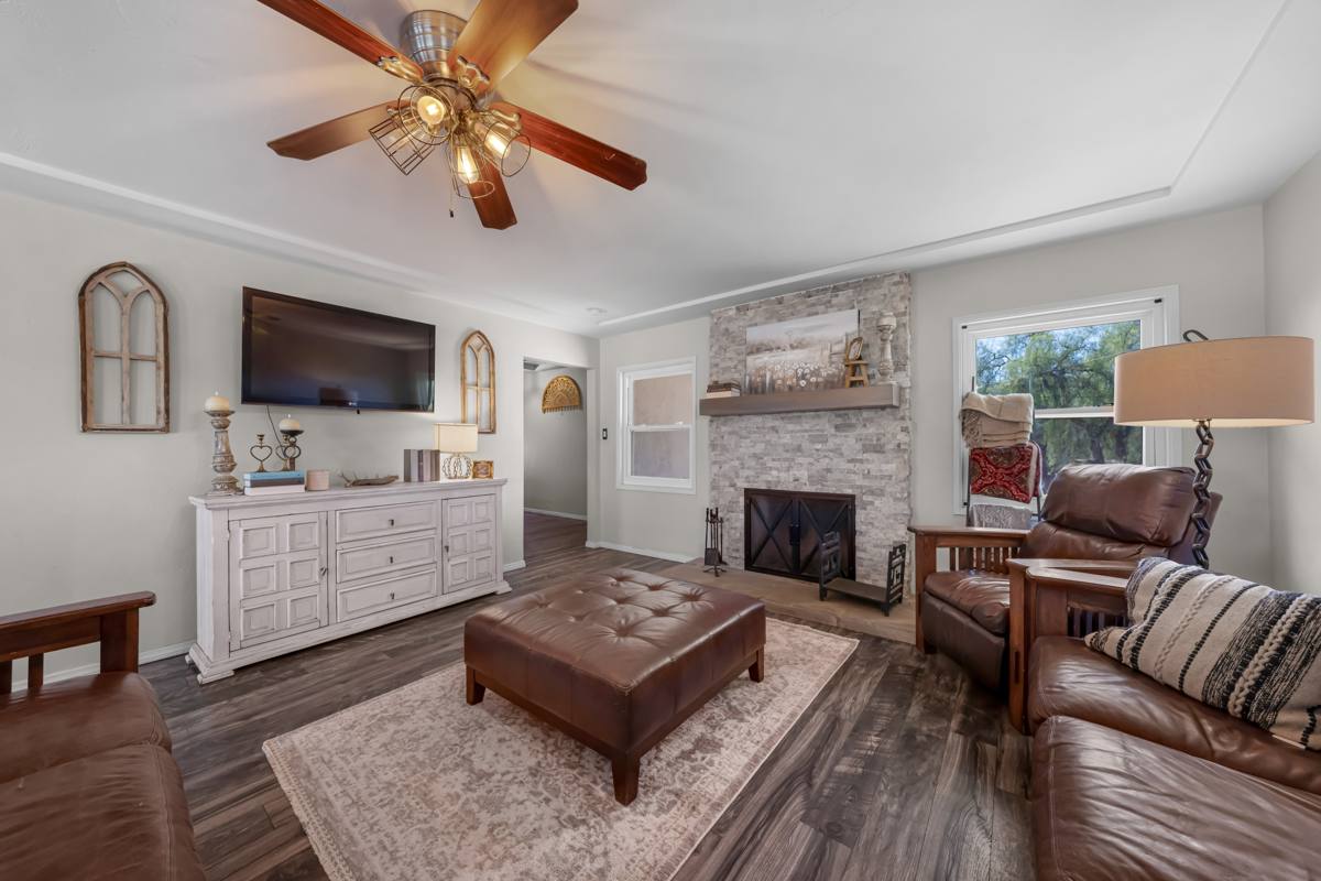 Living room with stacked-stone fireplace and wood-look flooring