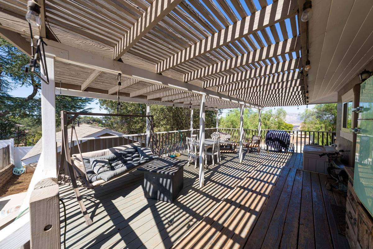 Pergola-covered deck with swing, dining table, and mountain views